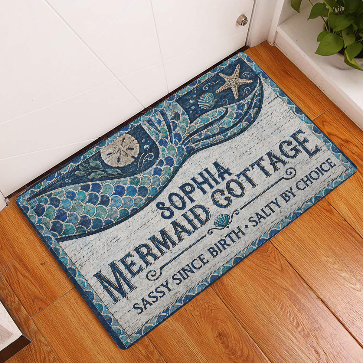Mermaid entryway rug displayed beside a white door on hardwood flooring with blue ocean-inspired artwork