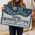 Mermaid doormat held indoors, showing detailed blue tail scales, seashells, starfish, and rustic coastal styling