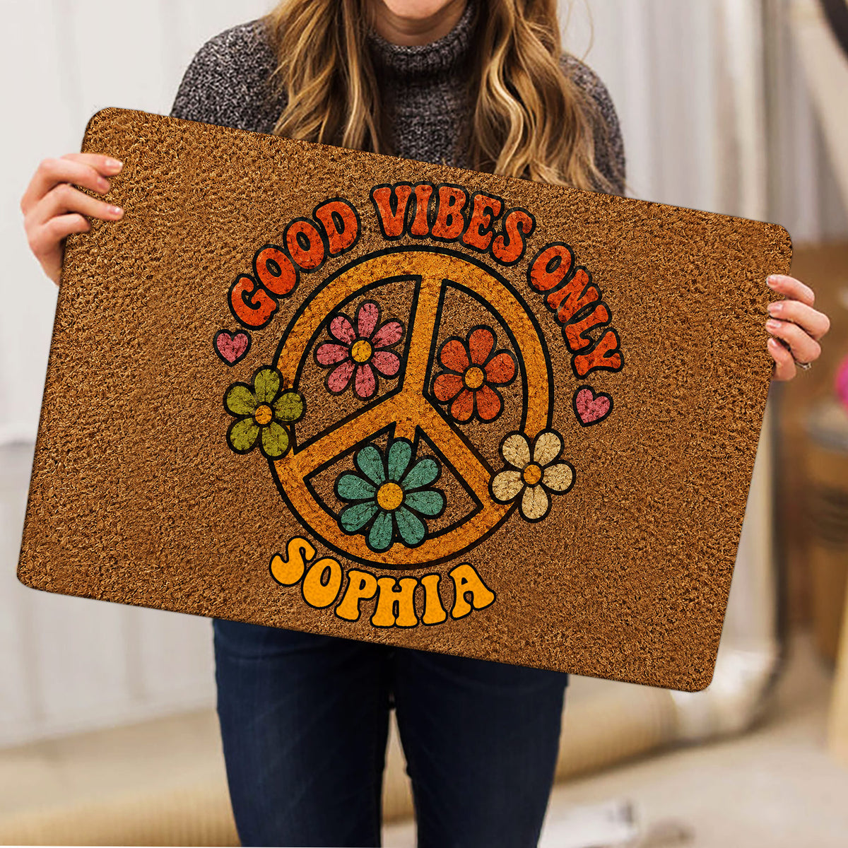 Person holding a colorful hippie peace sign flower doormat indoors