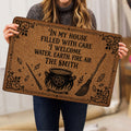 Person holding a Wicca doormat with cauldron, pentagram, broom, wand and crystal illustrations