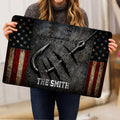 Fishing doormat held indoors, showing a large hook design, rugged metal texture, and patriotic border