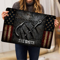 Fishing doormat held indoors, showing crossed hooks, rugged texture, stars, and red, white, and blue stripes