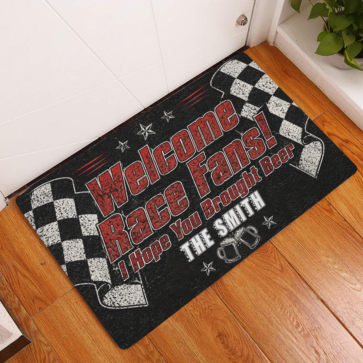 Racing-themed doormat displayed at a home entryway on a wood floor with checkered flags and red lettering
