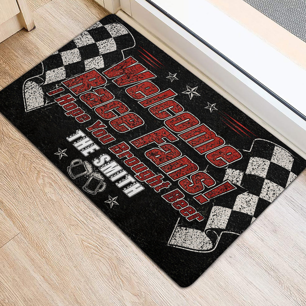 Race fan door mat positioned near a doorway, featuring black and red artwork with checkered racing flags