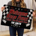 Race-themed doormat held indoors, showing checkered flags, stars, beer mugs, and dramatic black and red artwork