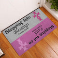 Breast cancer awareness entryway doormat displayed beside a white door on a wood floor