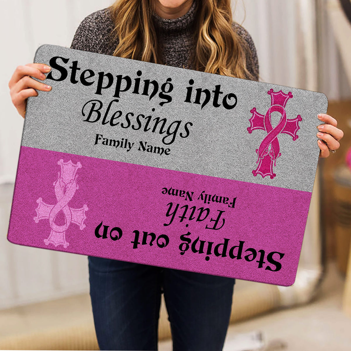 Person holding a pink and gray breast cancer awareness doormat with inspirational ribbon artwork