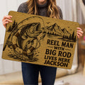 Person holding a fishing doormat featuring a large fish, rod, lure, mountains, and rustic brown design