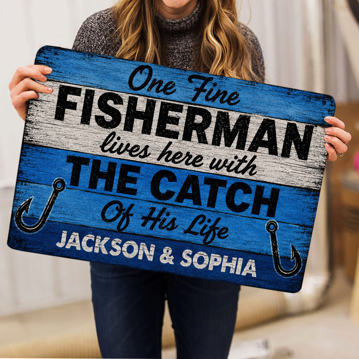 Person holding a blue fishing doormat with hook artwork and bold fisherman lettering