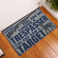 Hunting rifle and deer doormat displayed at a home entrance on a warm wood floor