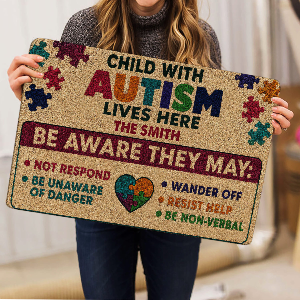 Person holding an autism awareness doormat featuring colorful puzzle pieces, a heart design, and supportive message