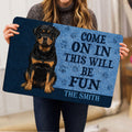 Rottweiler doormat held indoors, showing the full black and tan dog design and welcoming entryway artwork