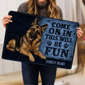 Person holding a German Shepherd doormat featuring blue artwork, paw prints, and welcome lettering
