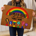 Person holding a colorful LGBT doormat featuring a rainbow, equality symbols, and affirming artwork