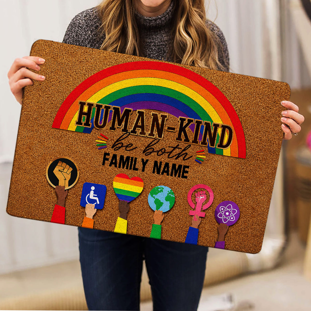 Person holding a colorful LGBT doormat featuring a rainbow, equality symbols, and affirming artwork