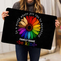 Person holding a black LGBT doormat featuring a vibrant rainbow flower design