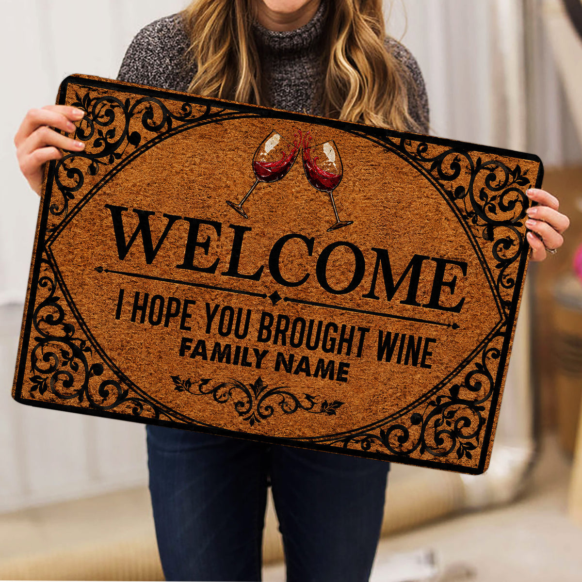 Wine-themed welcome doormat shown in a lifestyle presentation with red wine glasses and scrollwork