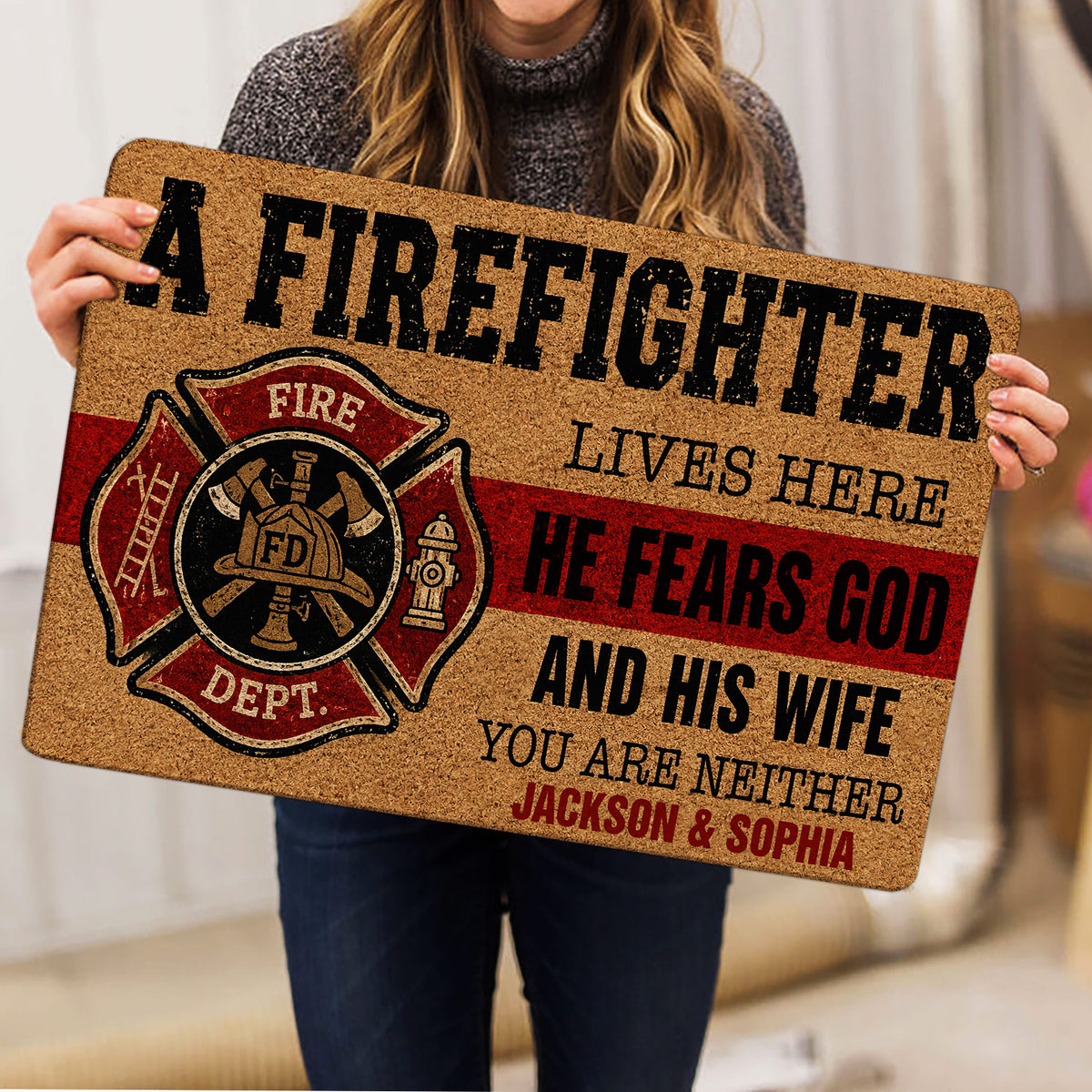 Person holding a firefighter doormat featuring a fire department emblem and bold lettering
