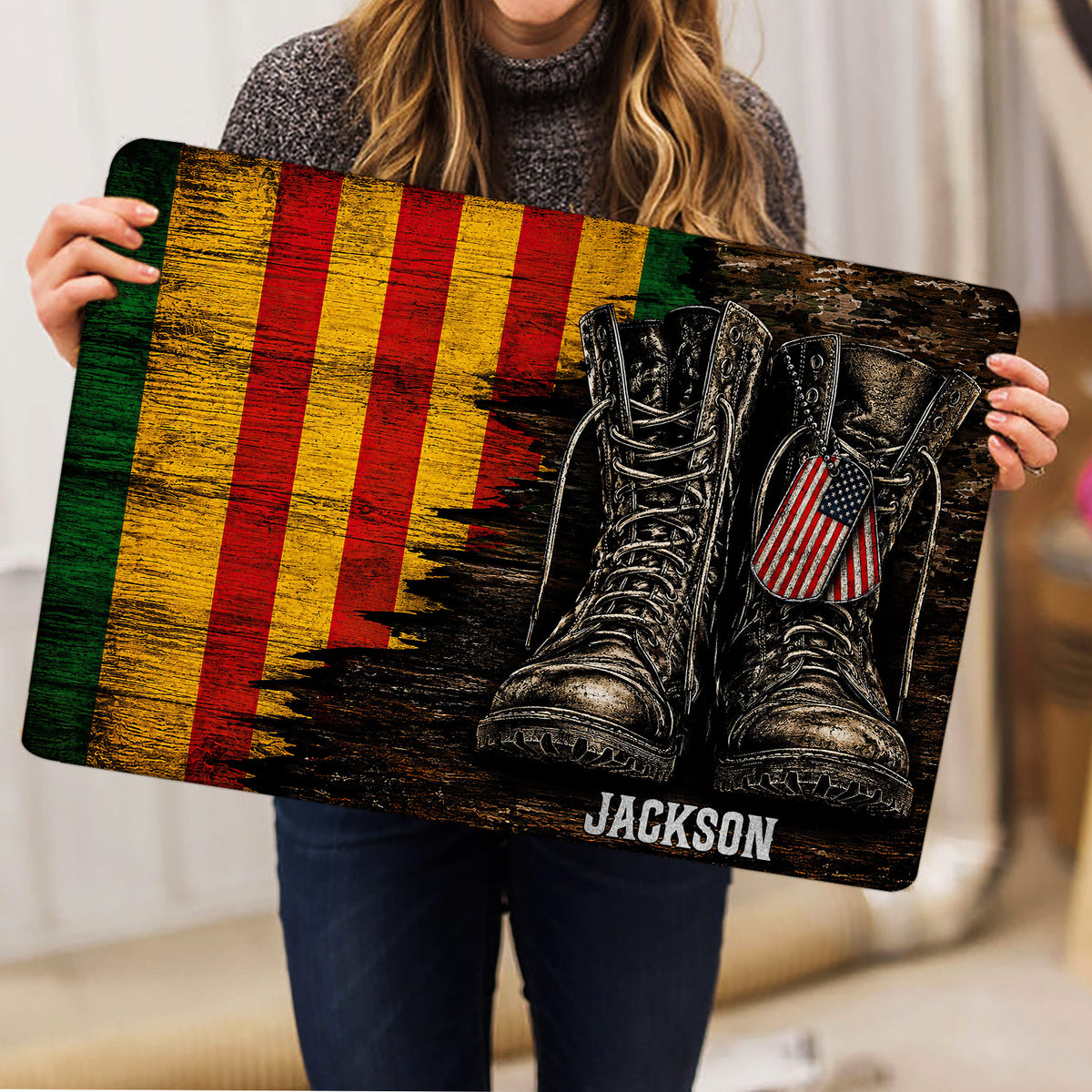Person holding a Vietnam Veteran doormat featuring combat boots, dog tags, and patriotic artwork