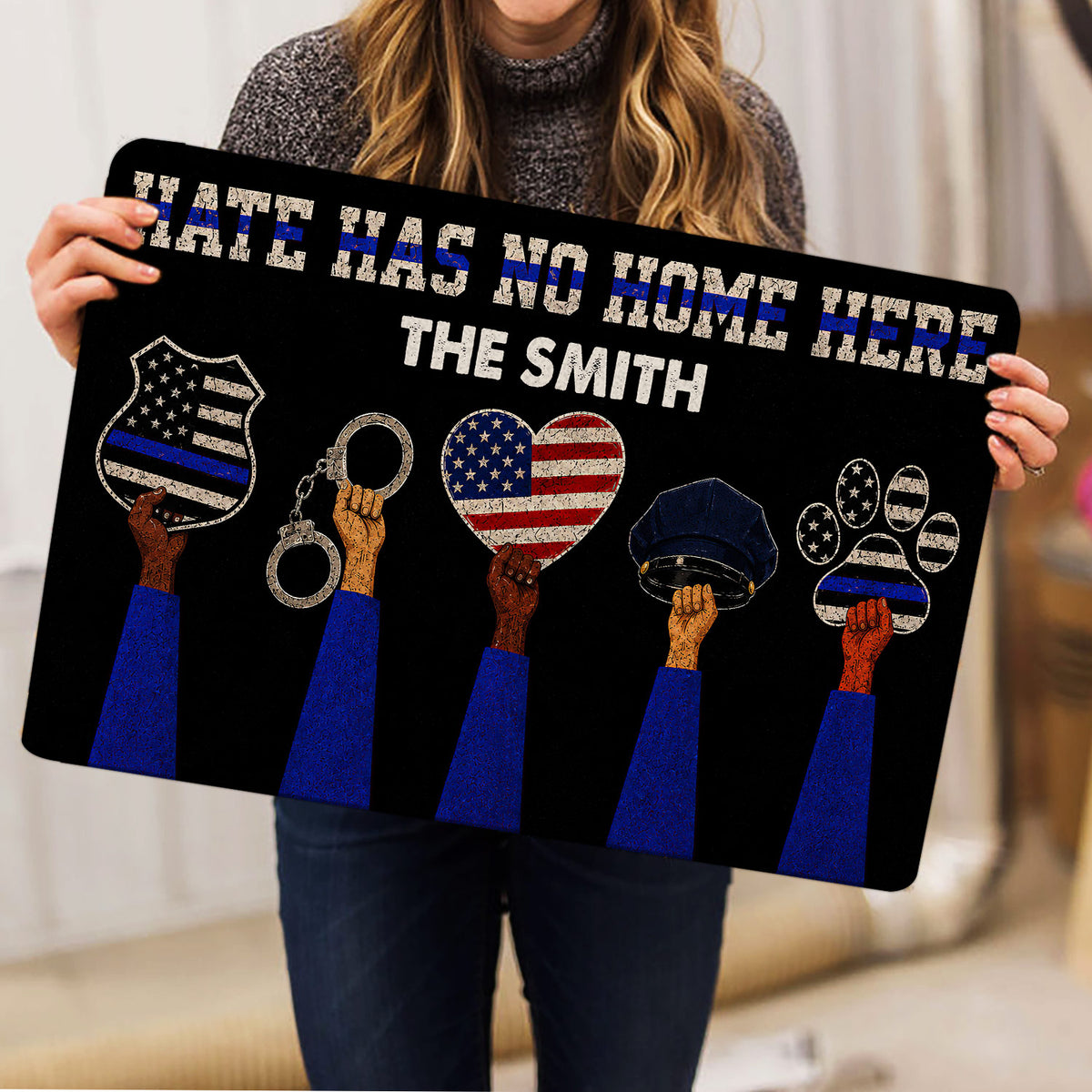 Person holding a police-themed doormat featuring badge, handcuffs, police hat, paw artwork, and patriotic blue-line colors
