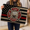 Firefighter mat held indoors, showing the detailed emblem, helmet, hydrant, ladder, and axes