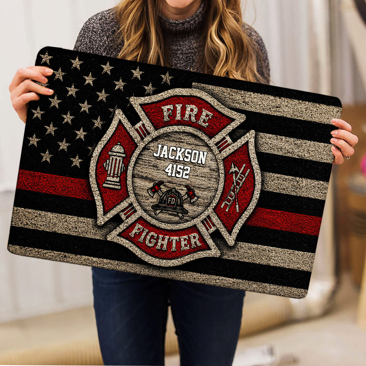 Firefighter mat held indoors, showing the detailed emblem, helmet, hydrant, ladder, and axes