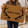 Hunting doormat held indoors, showing the tan textured artwork and black antler border