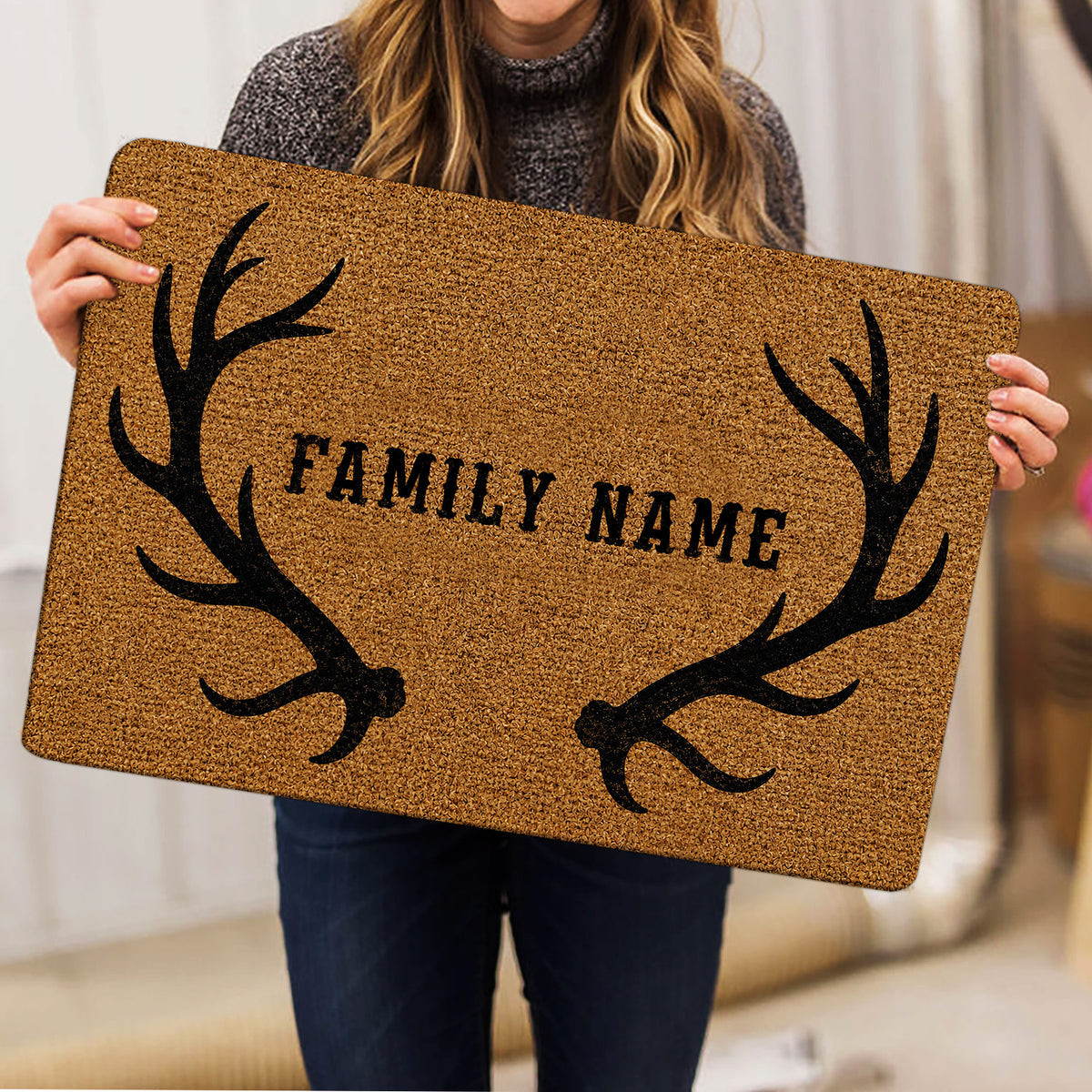 Hunting doormat held indoors, showing the tan textured artwork and black antler border