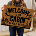 Person holding a hunting doormat featuring deer, antlers, trees, and rustic artwork