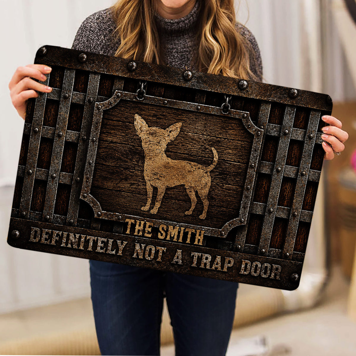 Person holding a rustic Chihuahua doormat featuring a framed dog portrait and playful message