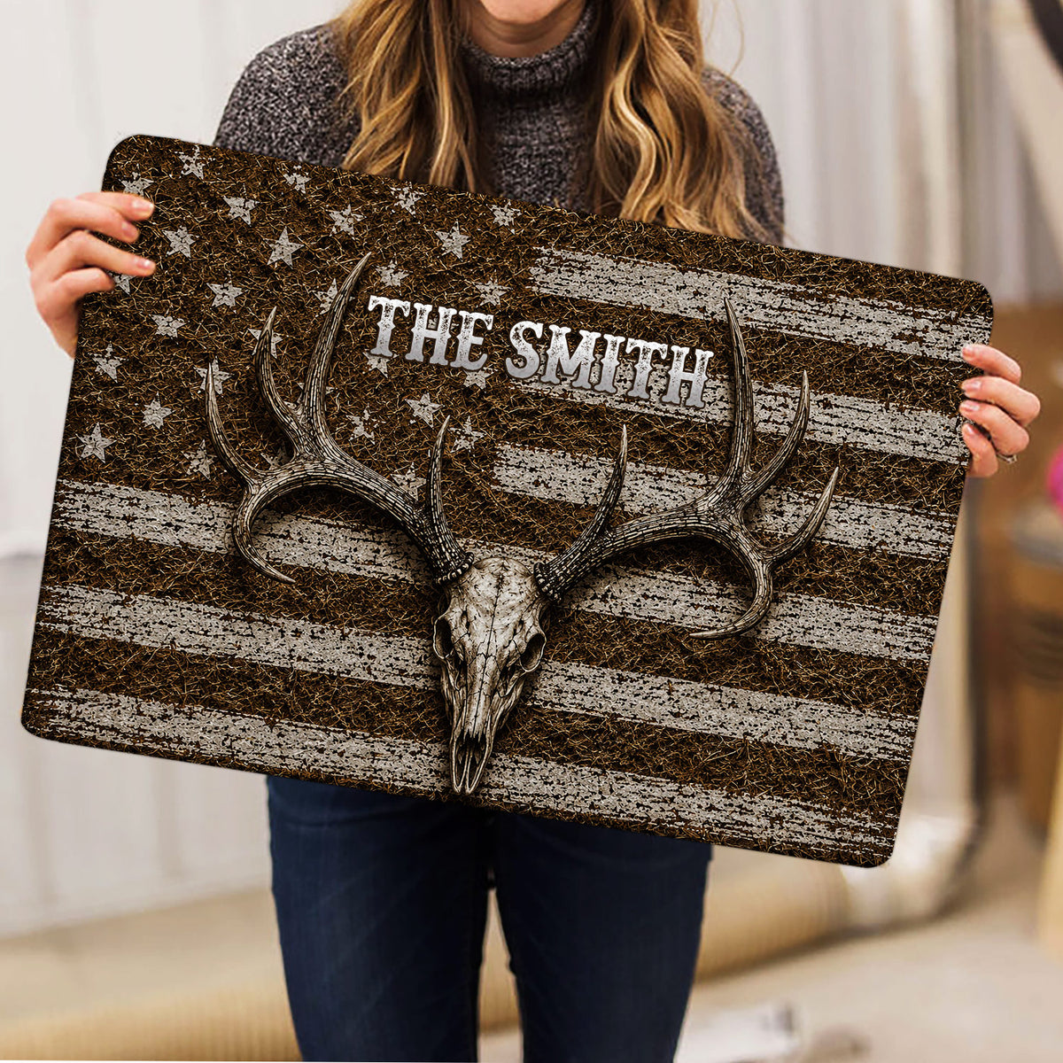 Hunting doormat held indoors, showing an antlered deer skull and distressed patriotic-style artwork