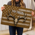 Person holding a hunting doormat featuring a deer skull, oversized antlers, stars and distressed stripes