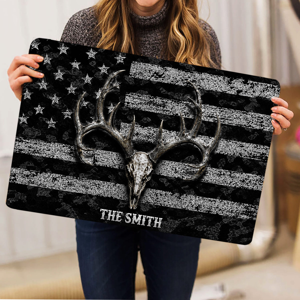 Lifestyle view of a person holding a hunting doormat featuring a deer skull and antler design