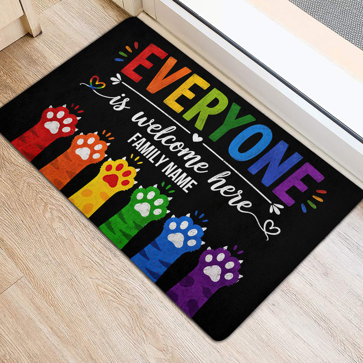 Colorful LGBT entryway rug positioned beside a doorway with rainbow lettering and paw-print artwork