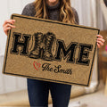 Person holding a tan veteran doormat featuring military boots, bold lettering and a black border