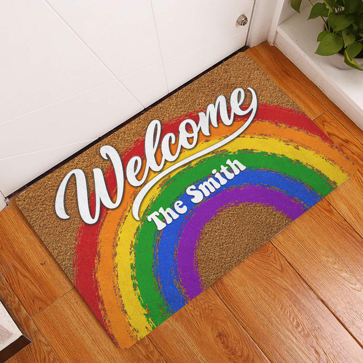 Rainbow Pride Welcome doormat displayed at a home entryway on a wood floor
