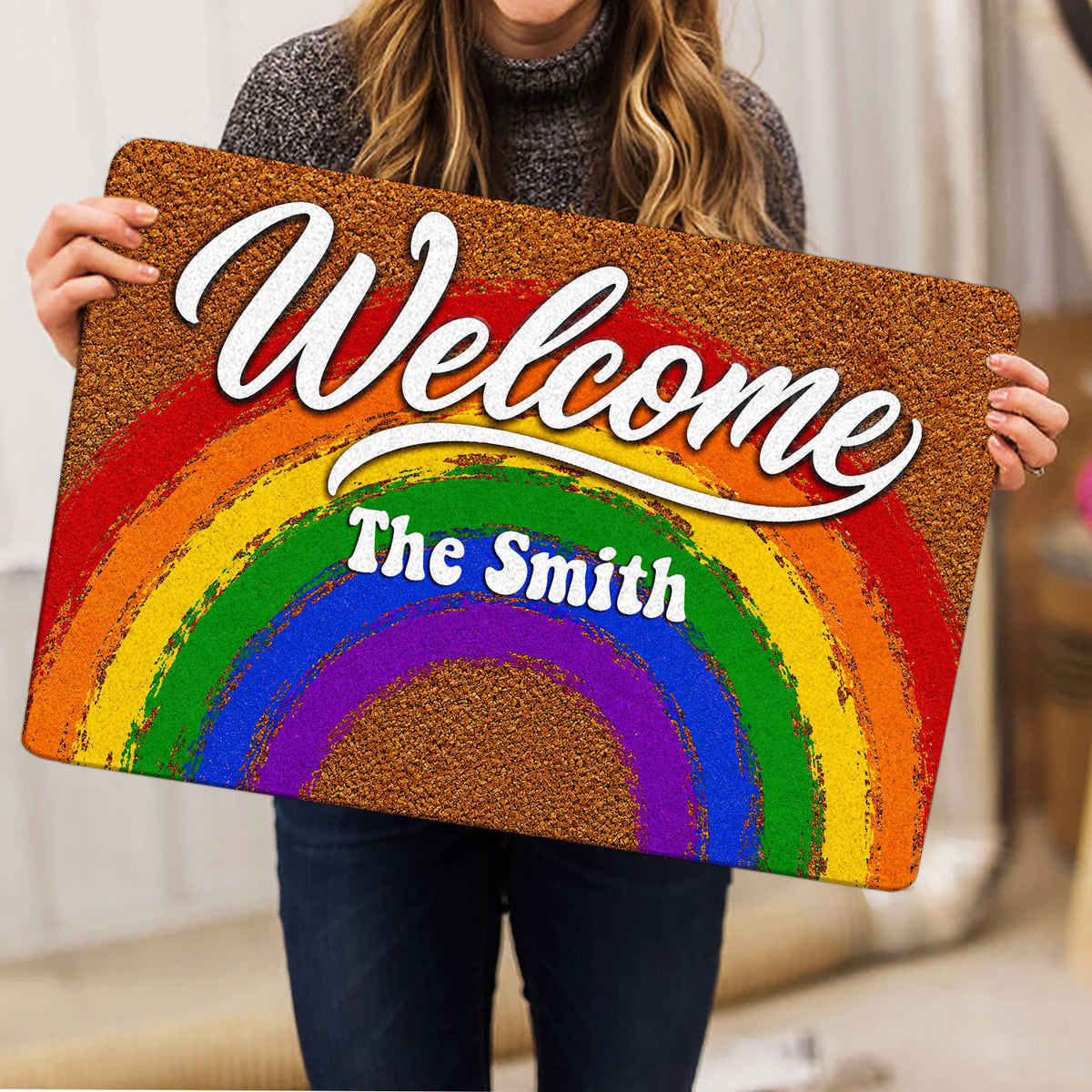 Rainbow Pride doormat held indoors, showing the bright Welcome artwork and colorful arc