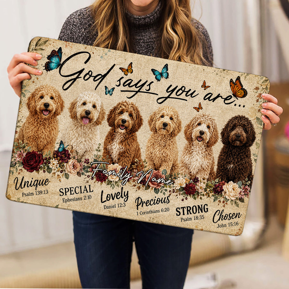 Woman holding a Goldendoodle doormat featuring six dogs, butterflies, flowers, and uplifting faith-inspired artwork