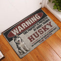 Husky warning-sign doormat displayed by an interior doorway on a wood floor