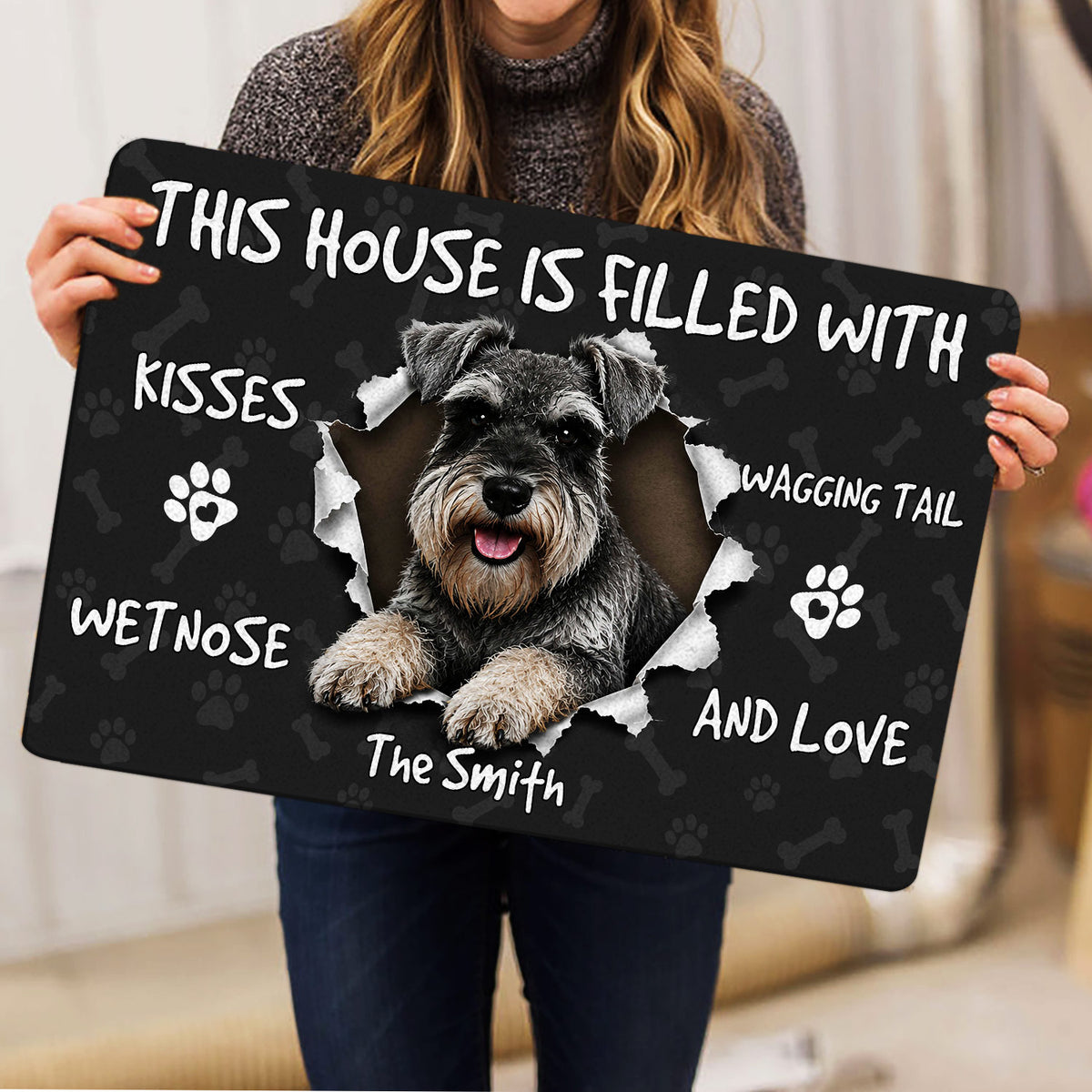 Person holding a Miniature Schnauzer doormat featuring a joyful dog portrait and dark paw print design