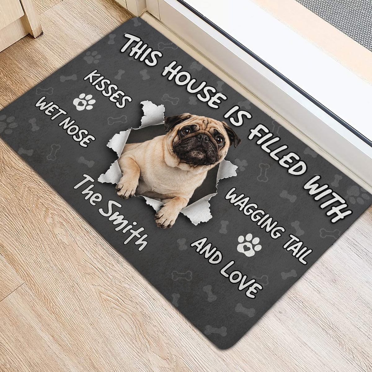 Pug doormat placed near a doorway, featuring a pug illustration, bones and paw prints