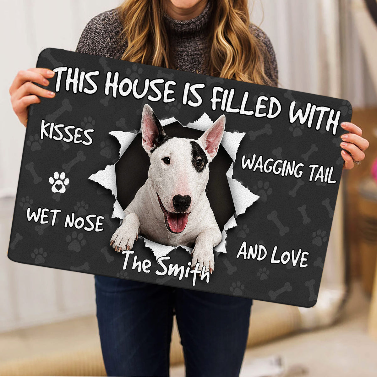 Person holding a Bull Terrier doormat featuring a white dog portrait and paw print artwork