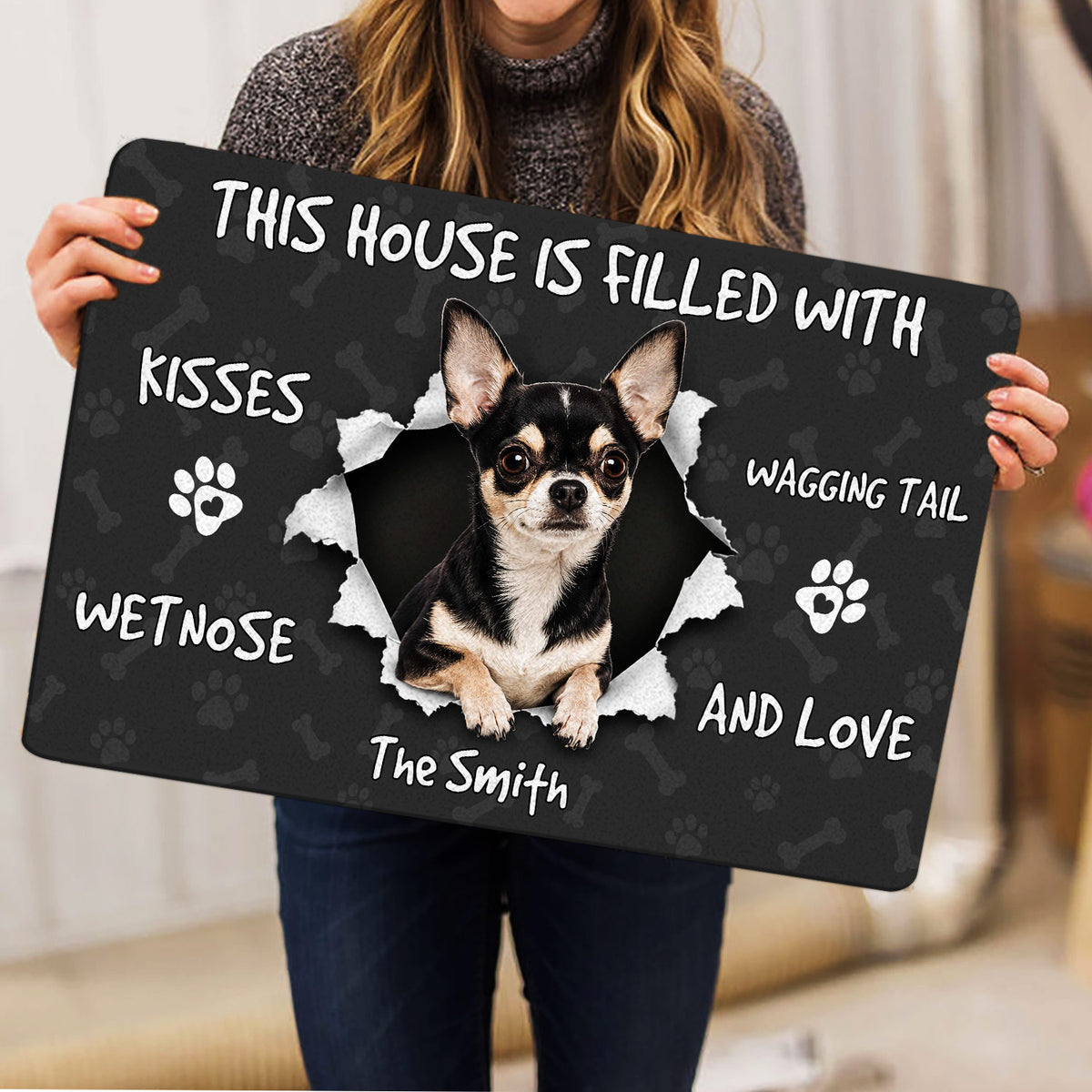 Person holding a Chihuahua doormat featuring a dog portrait, paw prints, bones, and welcoming lettering