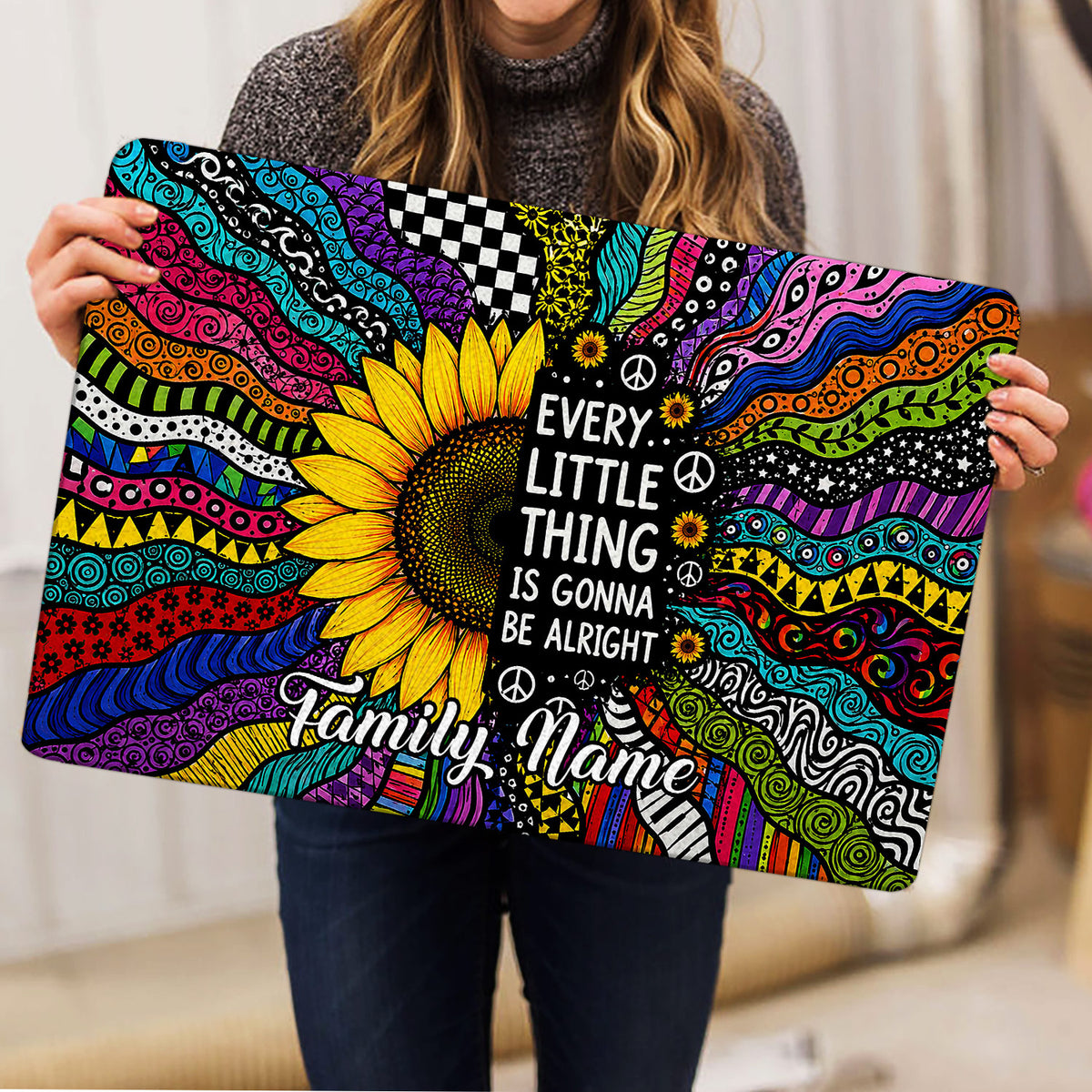 Person holding a colorful hippie sunflower doormat with psychedelic patterns and an uplifting message