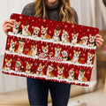 Corgi Christmas doormat held indoors, showing the full red design with Santa hats, scarves, snowflakes, and ornaments