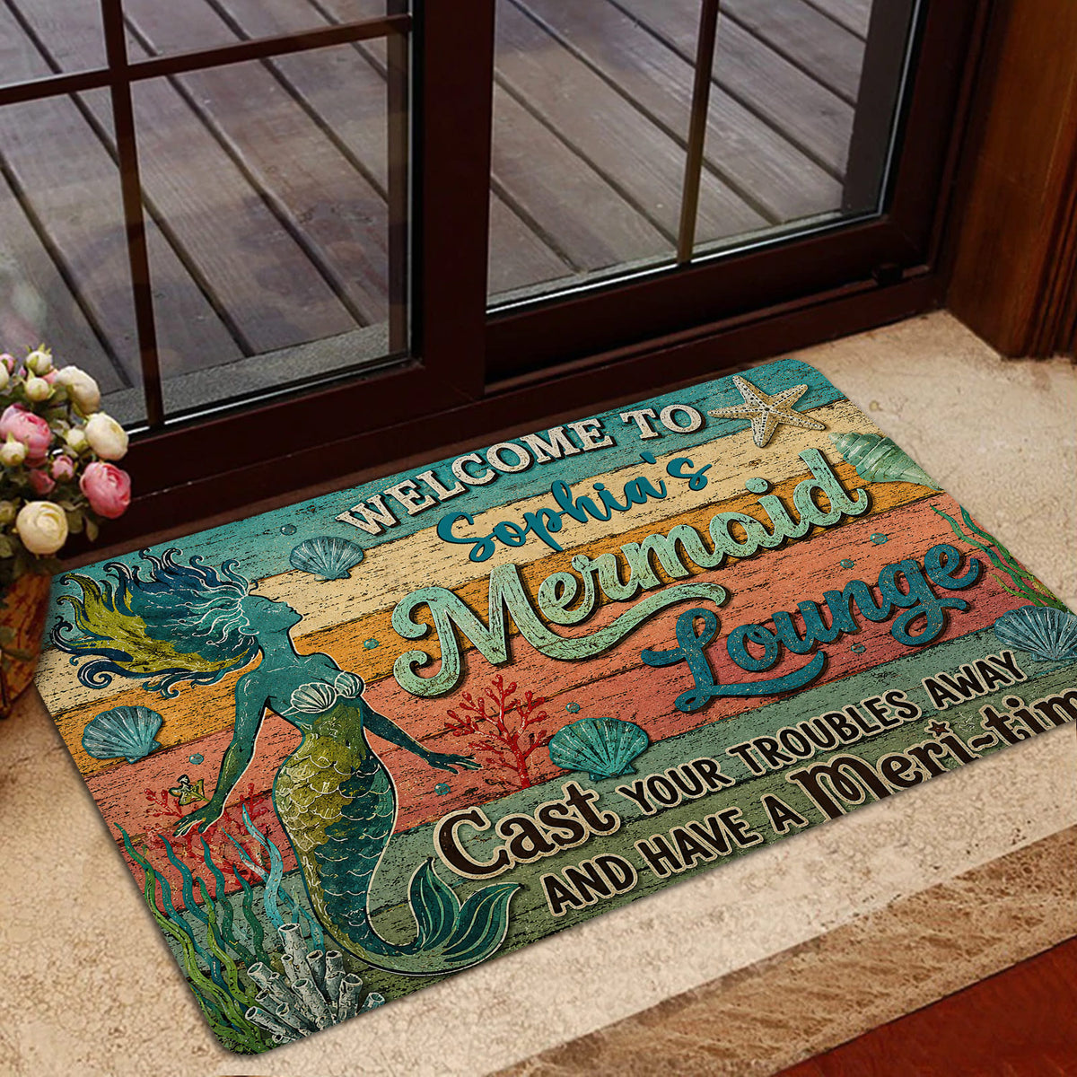 Mermaid welcome mat placed inside a glass doorway with an ocean-inspired design