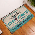 Mermaid saloon doormat styled at an indoor doorway on a warm wood floor