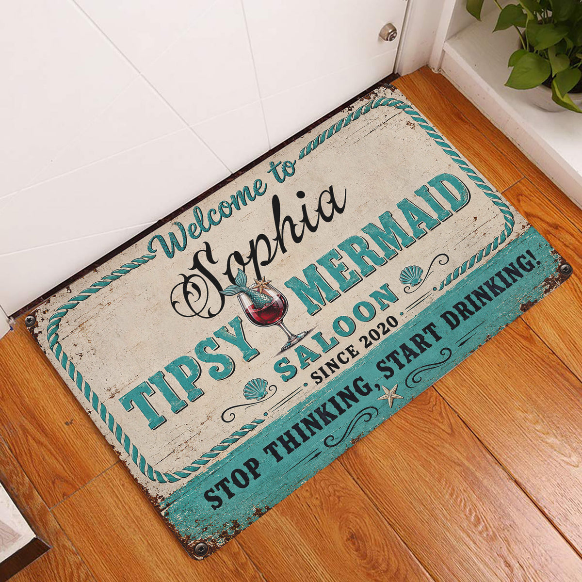 Mermaid saloon doormat styled at an indoor doorway on a warm wood floor
