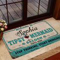 Mermaid-themed welcome mat placed near a glass door with coastal turquoise and vintage saloon artwork