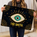Evil eye doormat held indoors, showing its large turquoise eye and ornate celestial design